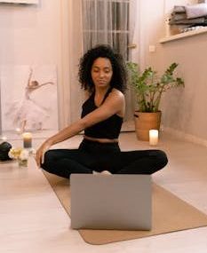 A woman engaged in a relaxing yoga session at home, using a laptop for guidance.
