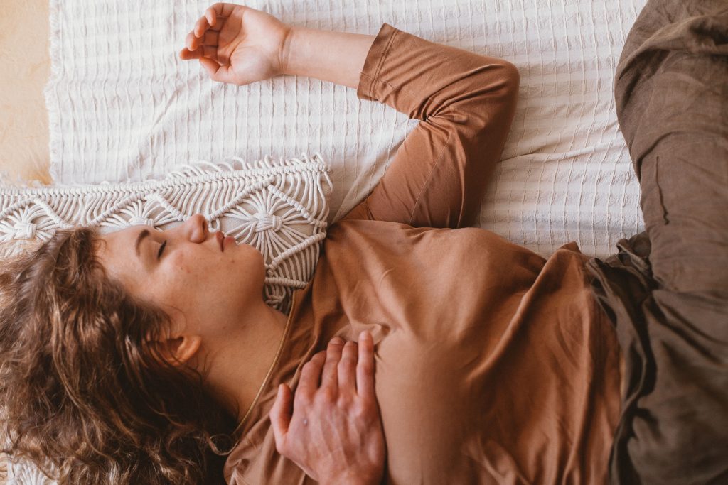 A serene image of a woman sleeping on a bed with sunlight filtering through. Perfect for lifestyle and relaxation themes.